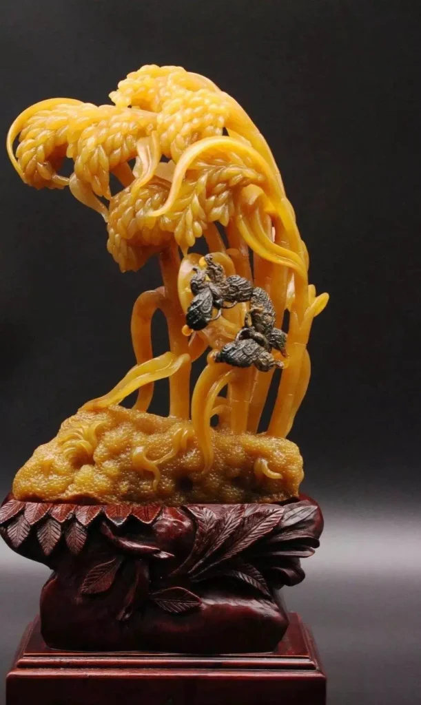 Intricate yellow Huoshan jade seed material carving featuring flowing wheat-like patterns and bees.