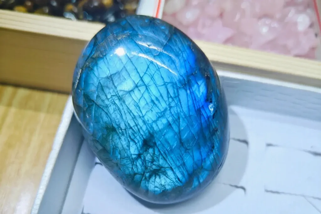 A polished, oval Inner Mongolia labradorite moonstone showing a vivid electric blue labradorescence under light.