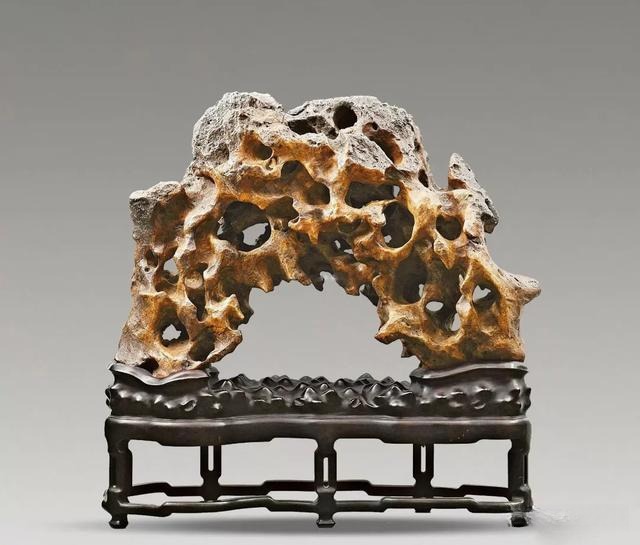 A horizontal porous Jiangsu Taihu stone titled "Dim Hollow Moon" on a carved dark wooden display stand.