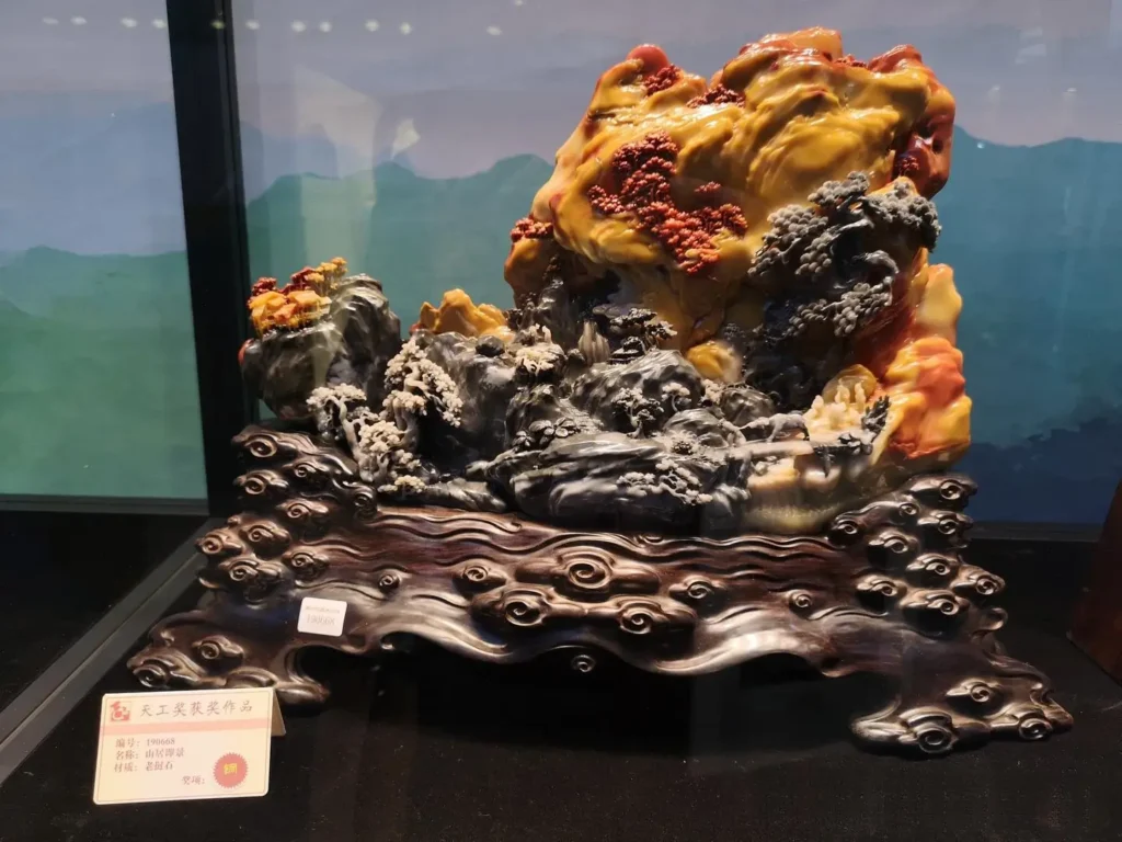 A detailed mountain landscape sculpture carved from multi-colored Laos stone.