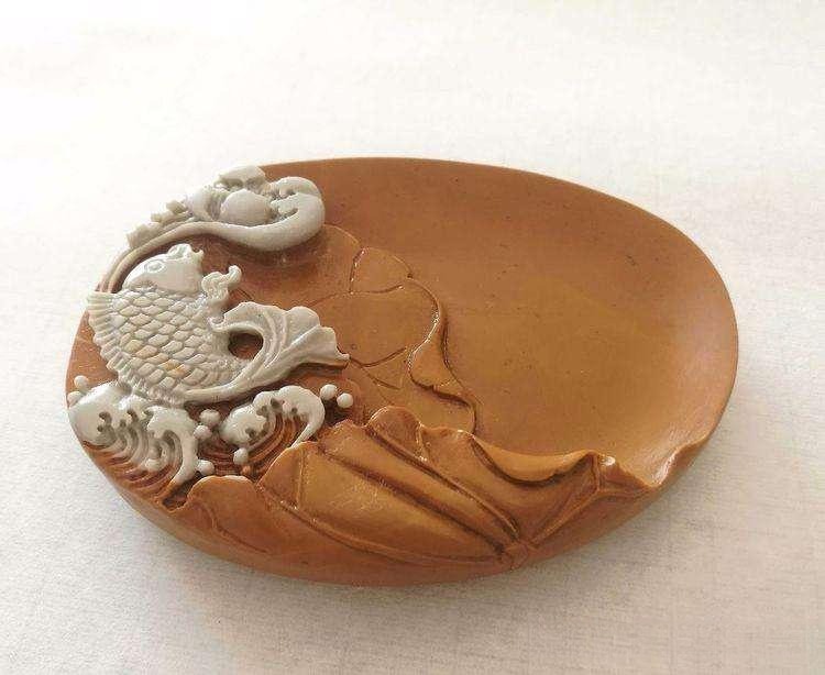 A traditional Chinese inkstone carved with a white carp leaping from waves.