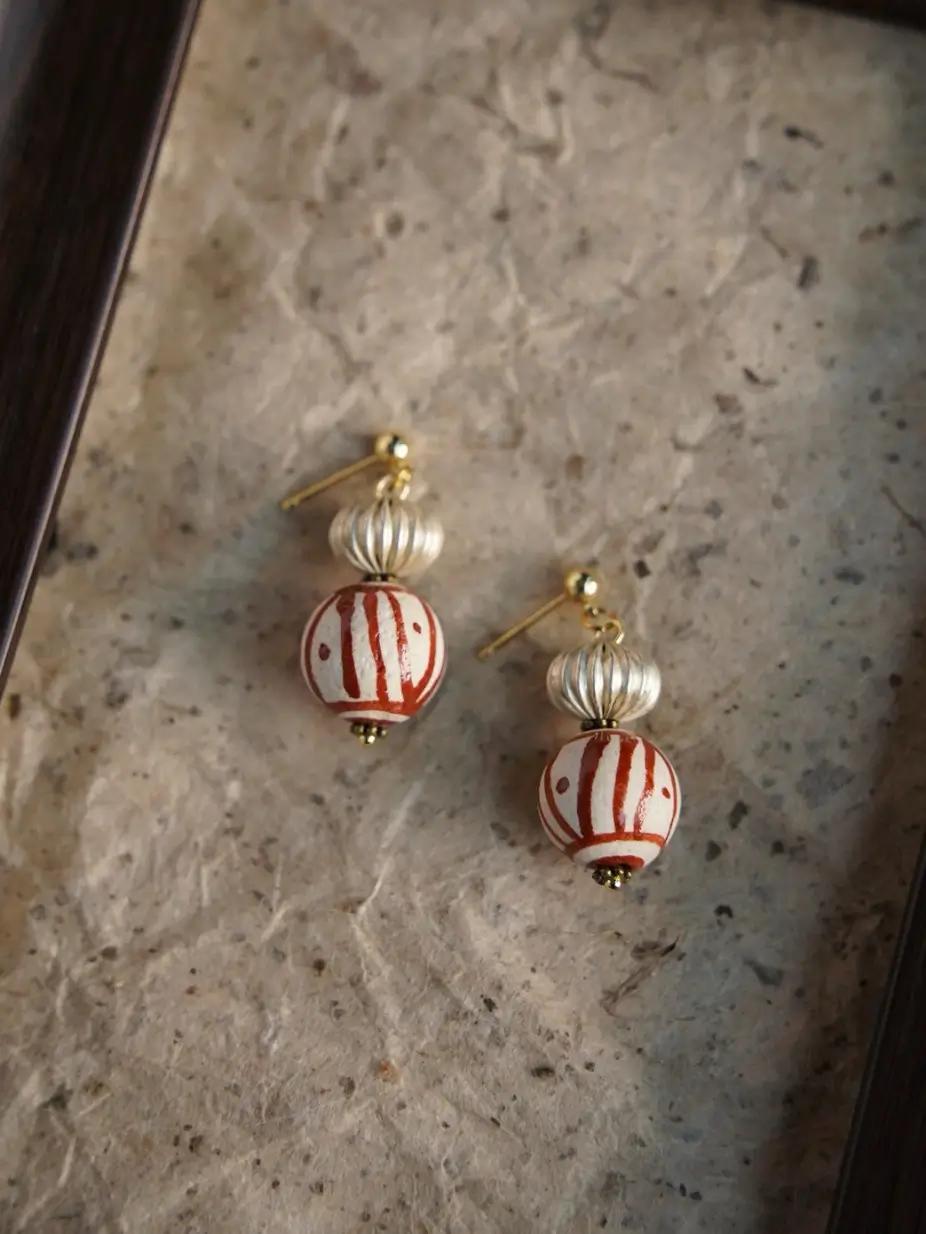 Macro of the red striped glass bead on this vintage earring, showing handcrafted texture.