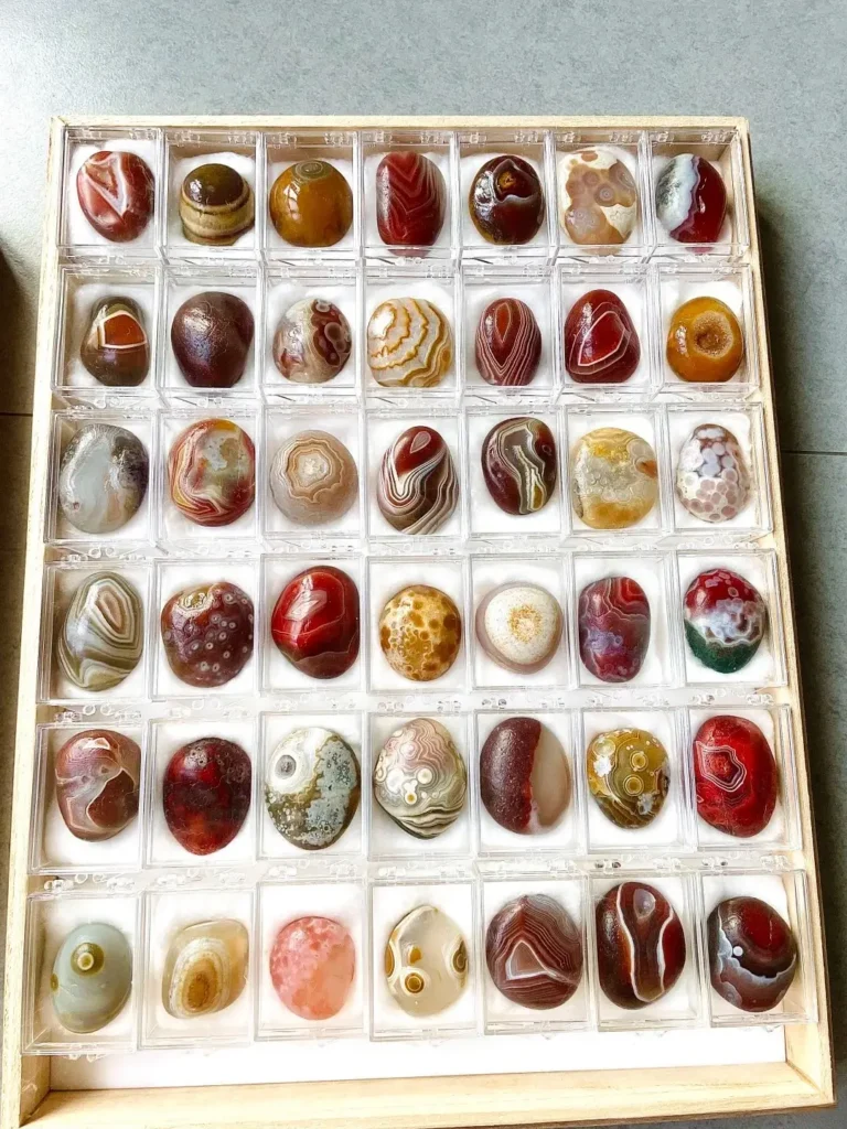 A collection of diverse Jiangsu Nanjing Yuhua stones with colorful patterns, neatly arranged in a grid box.