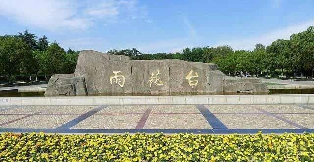 Large stone monument engraved with gold Chinese characters "Yuhua Terrace" in a scenic park.