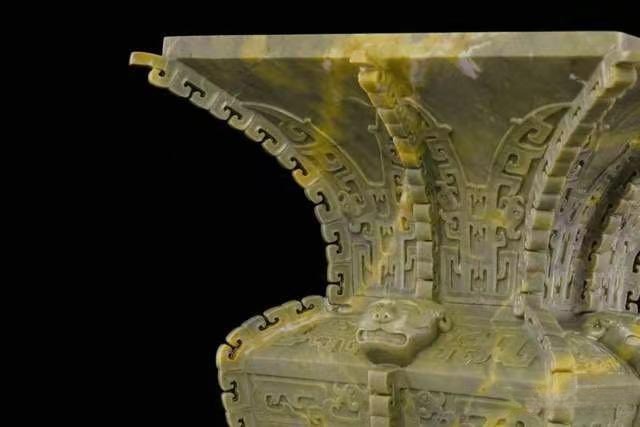 An ancient Chinese style vessel carved from yellowish-green Jilin Panlong jade with animal mask motifs.
