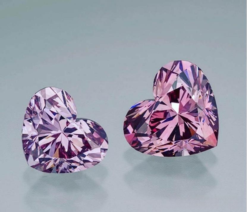 Two heart-shaped diamonds side by side, a pure purple diamond left and a pinkish purple diamond right.
