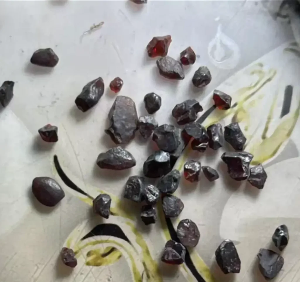 Unpolished, irregular dark red garnet rough stones and fragments from Heilongjiang, China.