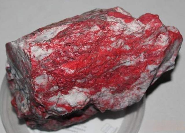 A raw Sandu chicken-blood stone rough from Guizhou showing bright red patches on white matrix.