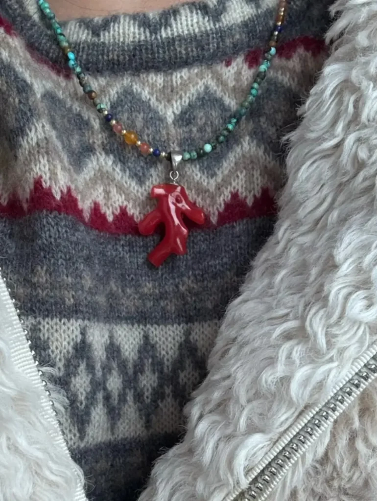 A red Taiwan coral branch pendant paired with a Dunhuang-inspired turquoise beaded necklace on a sweater.