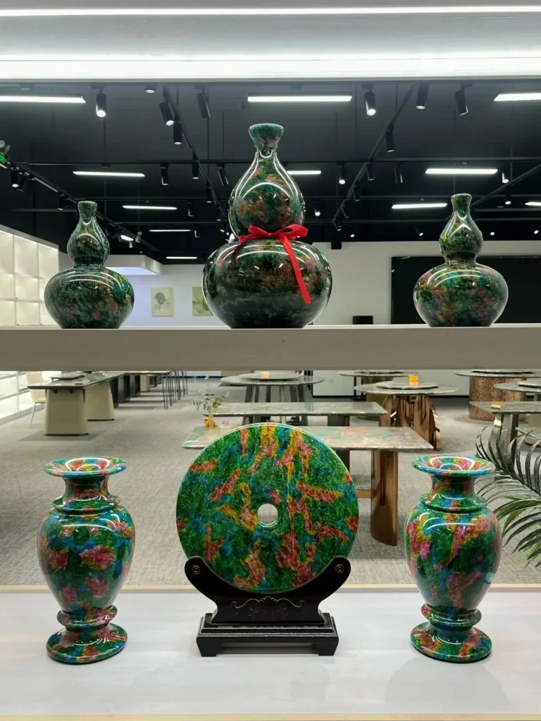 Multiple colorful glazed gourds, vases, and a bi-disc displayed on shelves in a showroom.