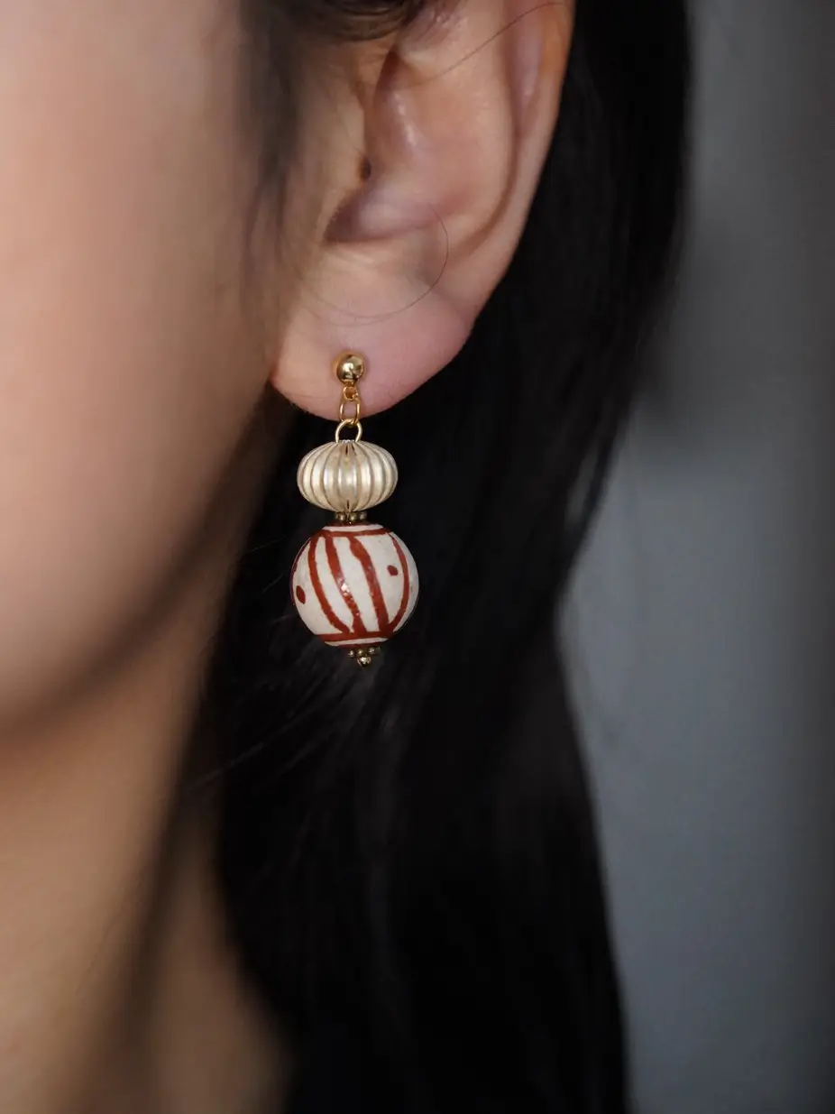 Close-up of a silver pendant earring hanging naturally on an earlobe.