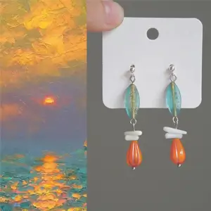 Flat-lay photograph of handcrafted earrings inspired by Claude Monet’s Impression, Sunrise (1872), featuring Czech glass and natural seashell elements.