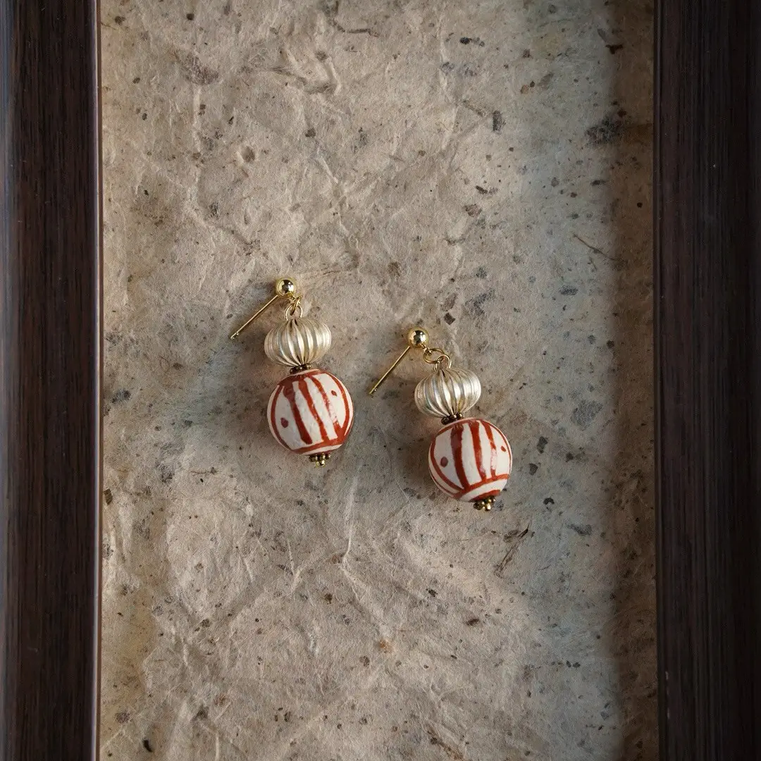 Vintage pendant stud earrings displayed on a piece of mottled, aged paper.
