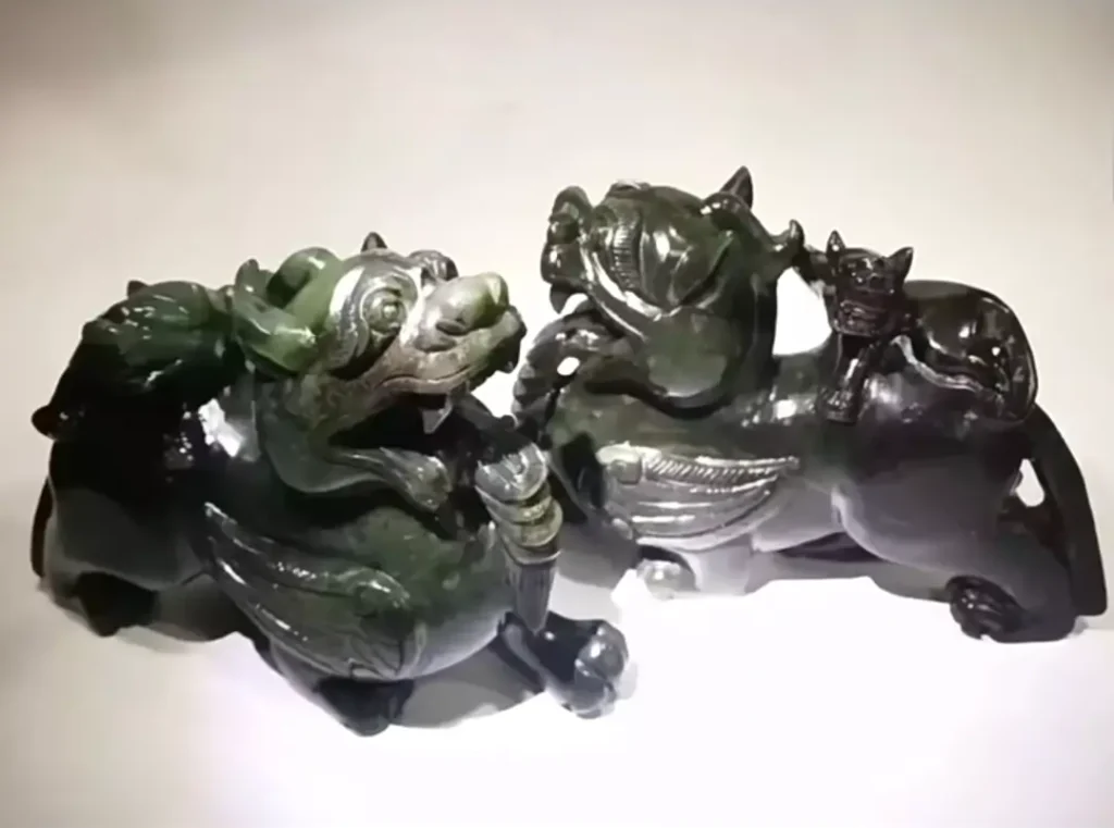 A pair of dark green Chinese mythical beast carvings made of Xianghua nephrite jade.