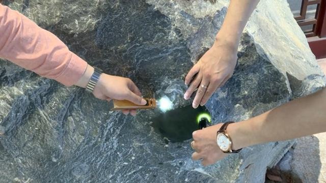 Experts using gemological torches to inspect a large rough block of green, emerging Xianghua nephrite.