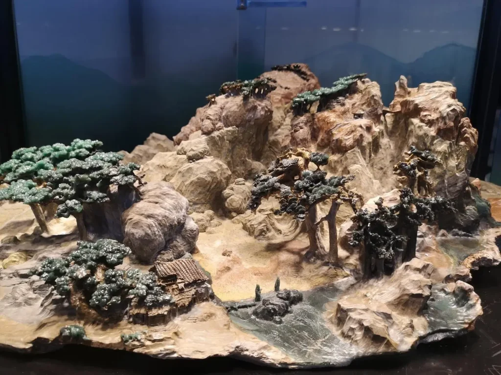 A panoramic mountain landscape with green trees carved from Ya'an Green Stone.