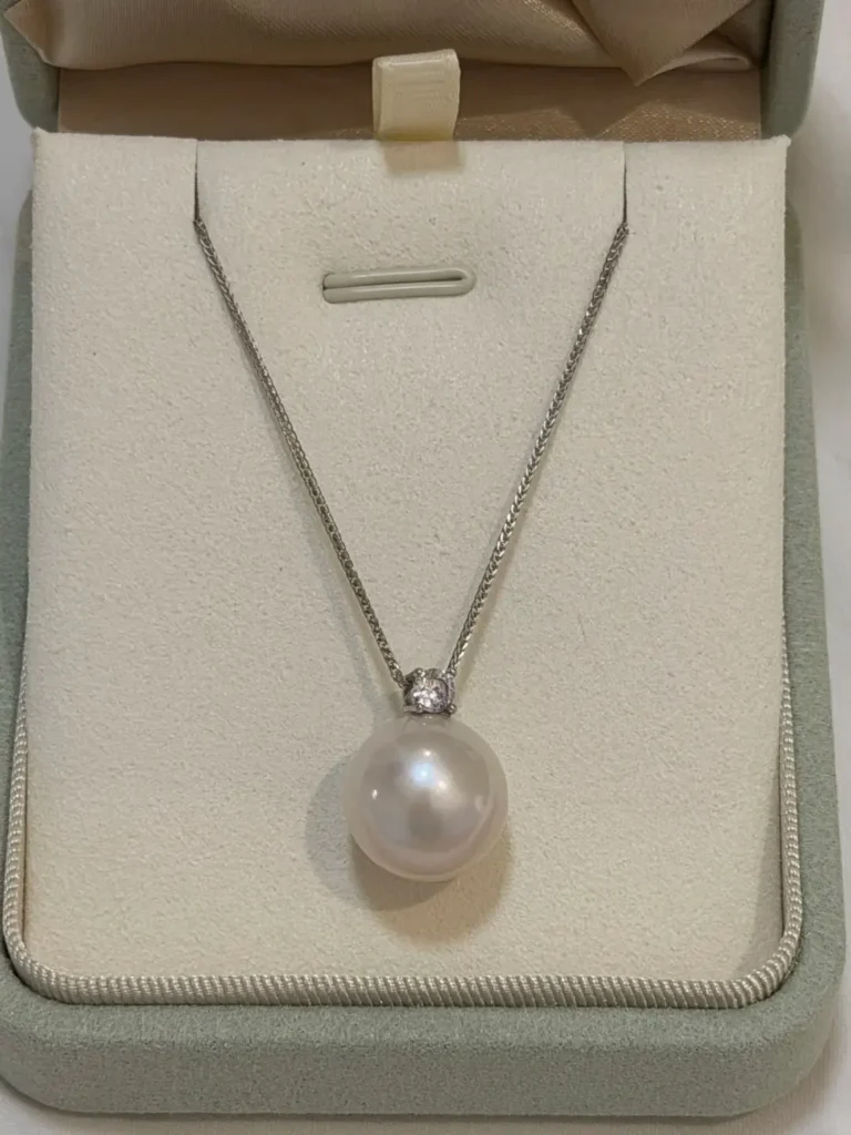 A single large white Edison pearl pendant on a silver chain rests inside a jewelry box.