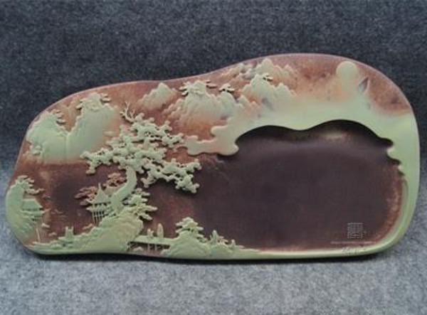 A traditional Chinese inkstone carved from layered purple and green stone.