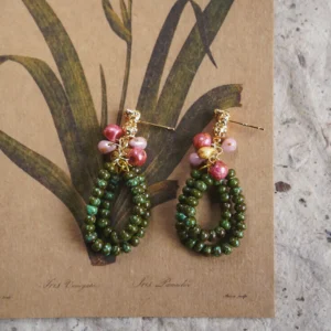 Handcrafted botanical beaded earrings featuring multi-layered green glass loops and pink accents.