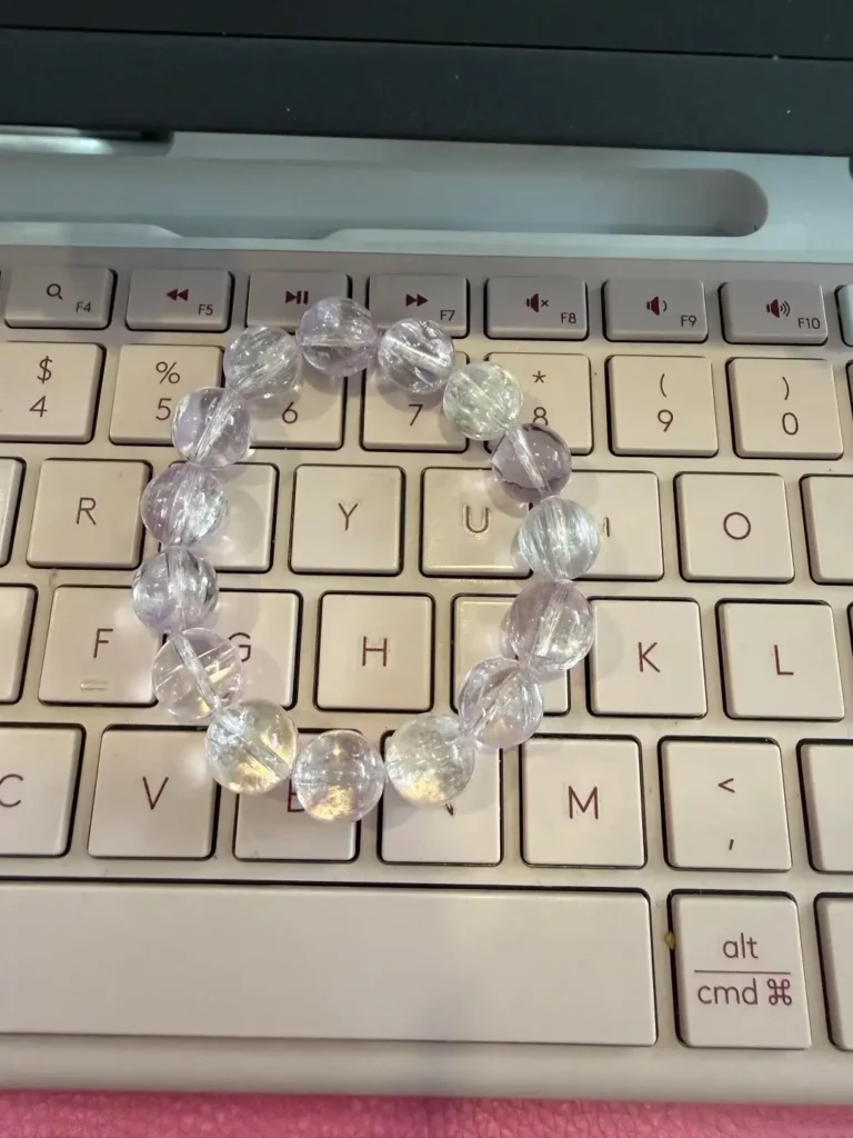 A faded, nearly colorless kunzite bead bracelet resting on a laptop keyboard.