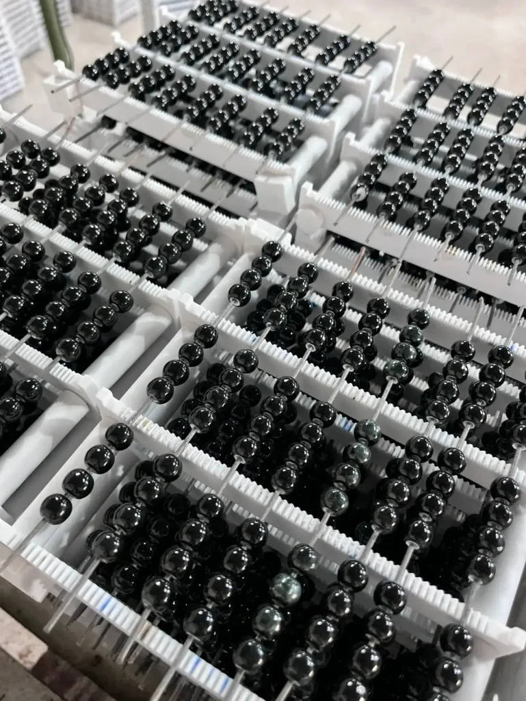 Glossy black vitrified ceramic beads arranged on fine wires after high-temperature firing.