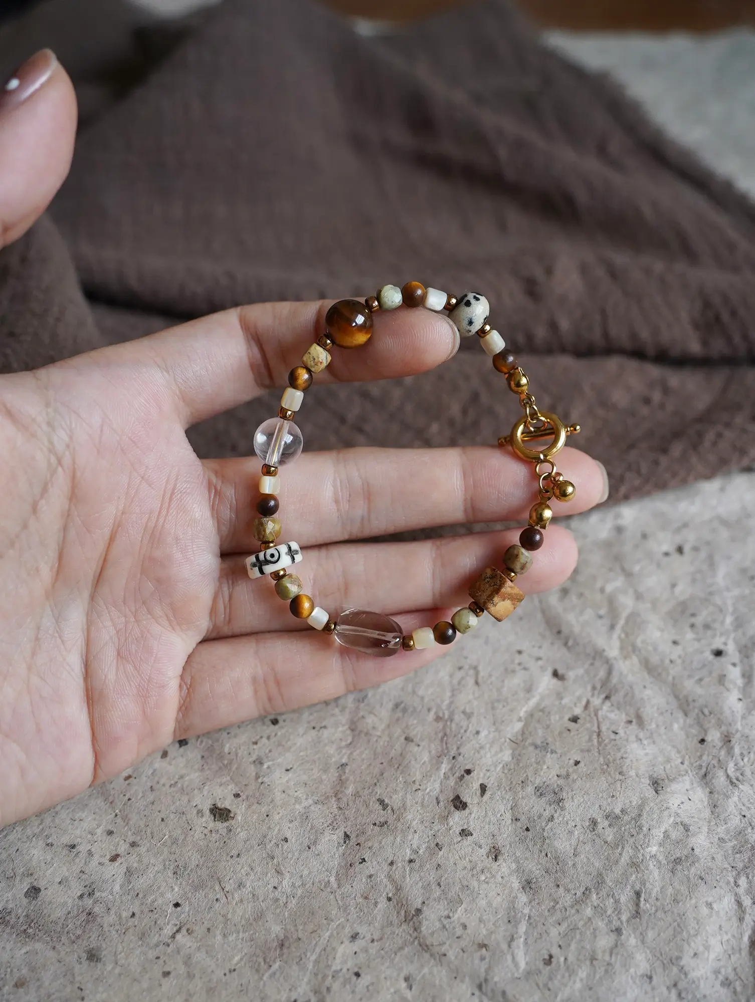 Hand holding natural stone bracelet with visible texture and detailed mineral patterns in close-up view.