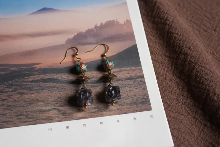 A pair of hand-carved ebony wood drop earrings with inlaid turquoise and agate beads on brass hooks.