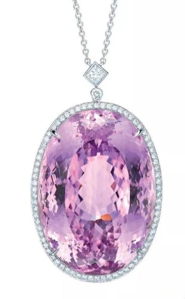 An oval pink kunzite pendant with a diamond halo, hanging from a platinum chain.