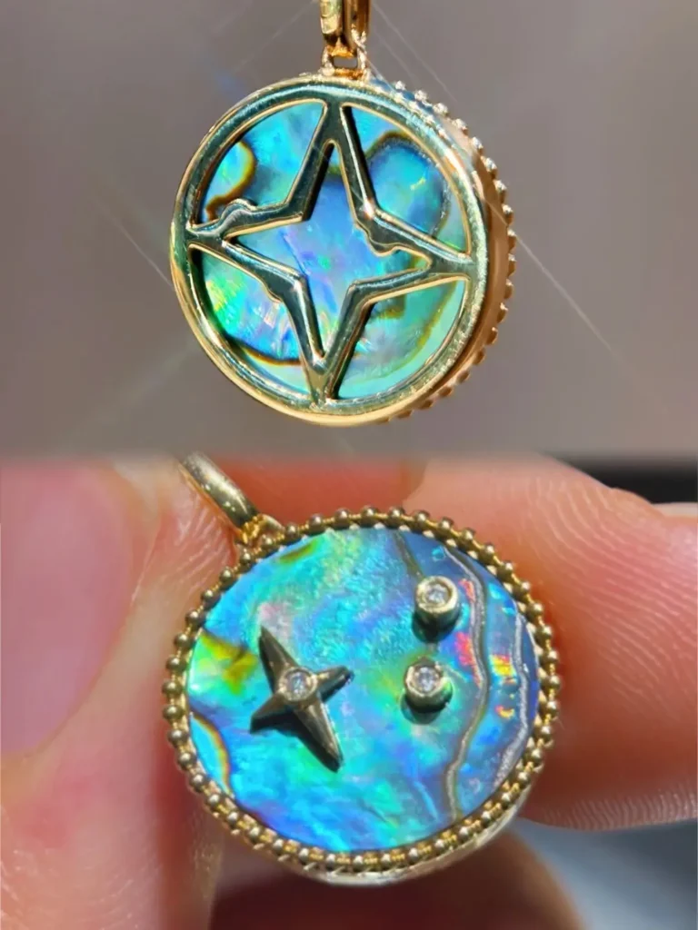 Round gold pendant featuring reversible abalone shell inlay with iridescent blue-green colors.
