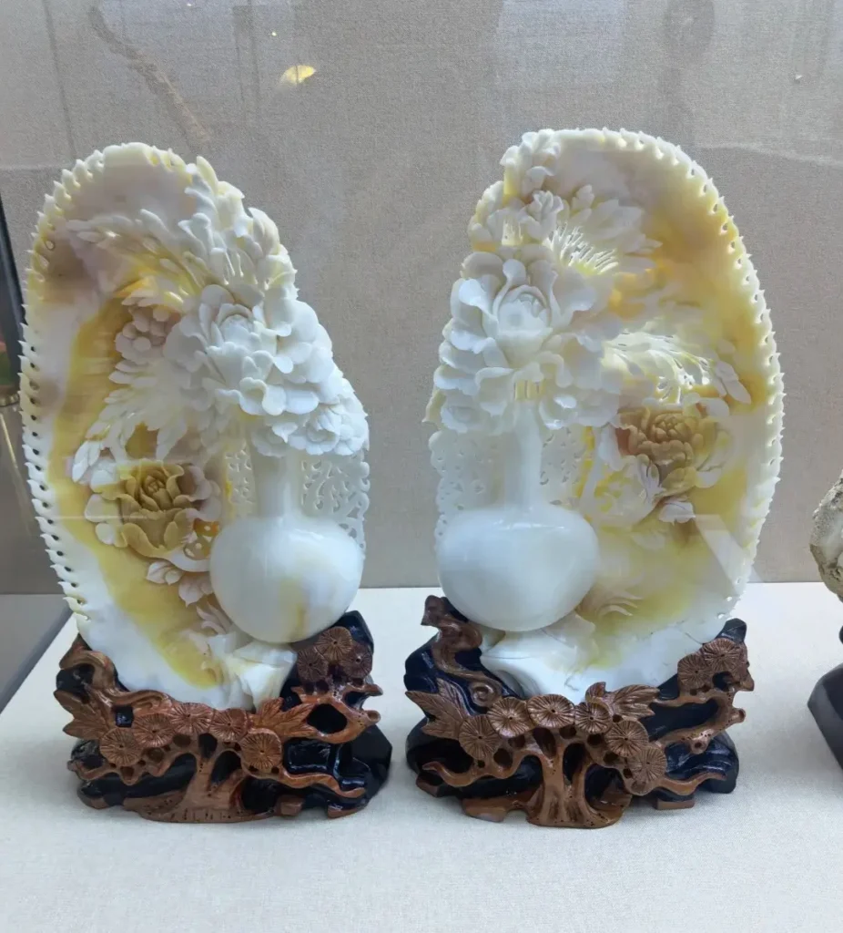 Carved Tridacna shell peony vase sculpture displayed at a marine shell culture museum.