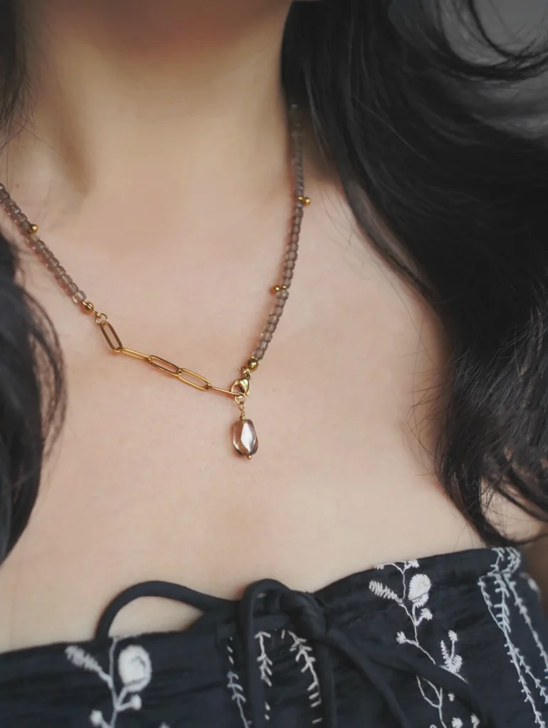 A woman with loose wavy dark hair wearing a handmade obsidian beaded necklace.