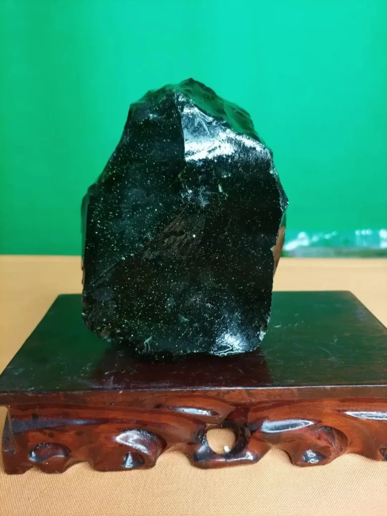 A gem-grade, translucent dark green tektite displaying natural surface erosion.