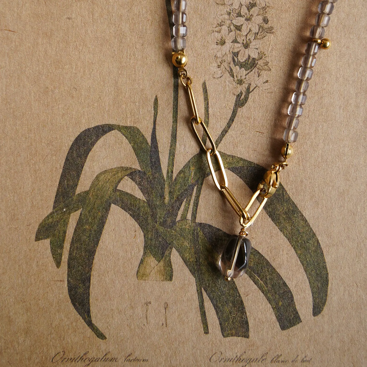 Close-up of a gold-plated titanium steel extension chain with an irregular smoky quartz pendant.