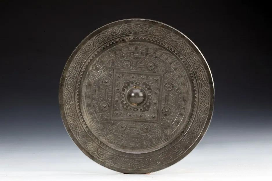 A circular Han bronze mirror with TLV patterns and a central four-petal floral motif.