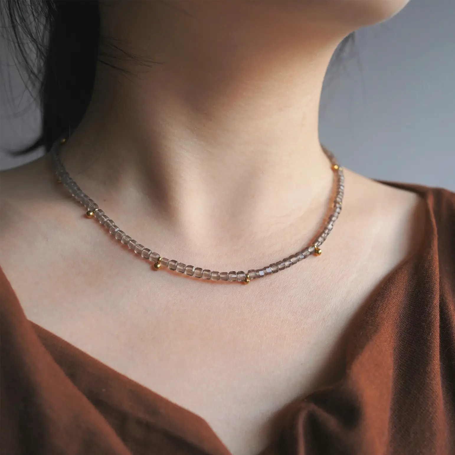 A woman wearing an ice obsidian beaded choker necklace resting close to her collarbone.