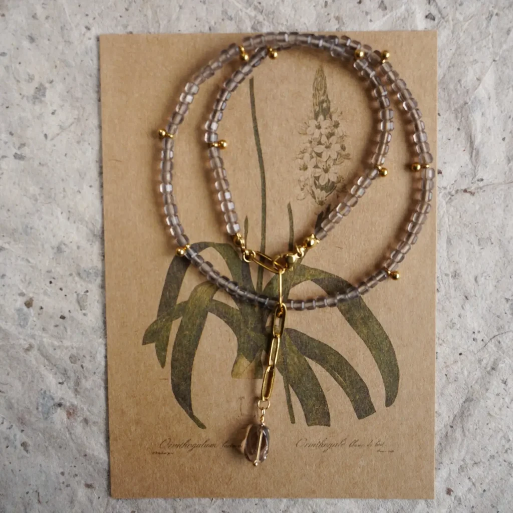 Handmade beaded necklace with a smoky quartz pendant on a vintage card.