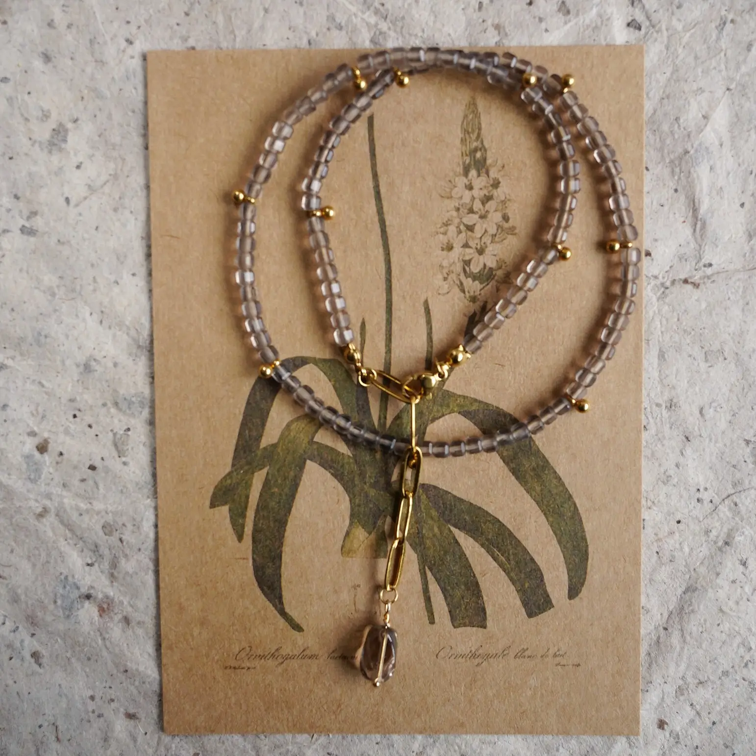 Handmade beaded ice obsidian necklace with a smoky quartz pendant on a vintage card.