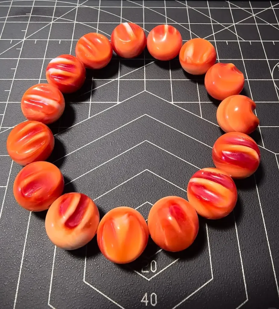 Polished Helmet Shell beads jewelry showing natural orange and reddish-orange colors.