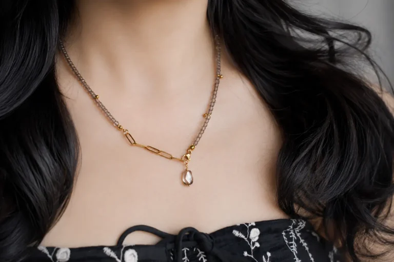 Woman wearing an ice obsidian beaded necklace with dark hair and a dark dress.