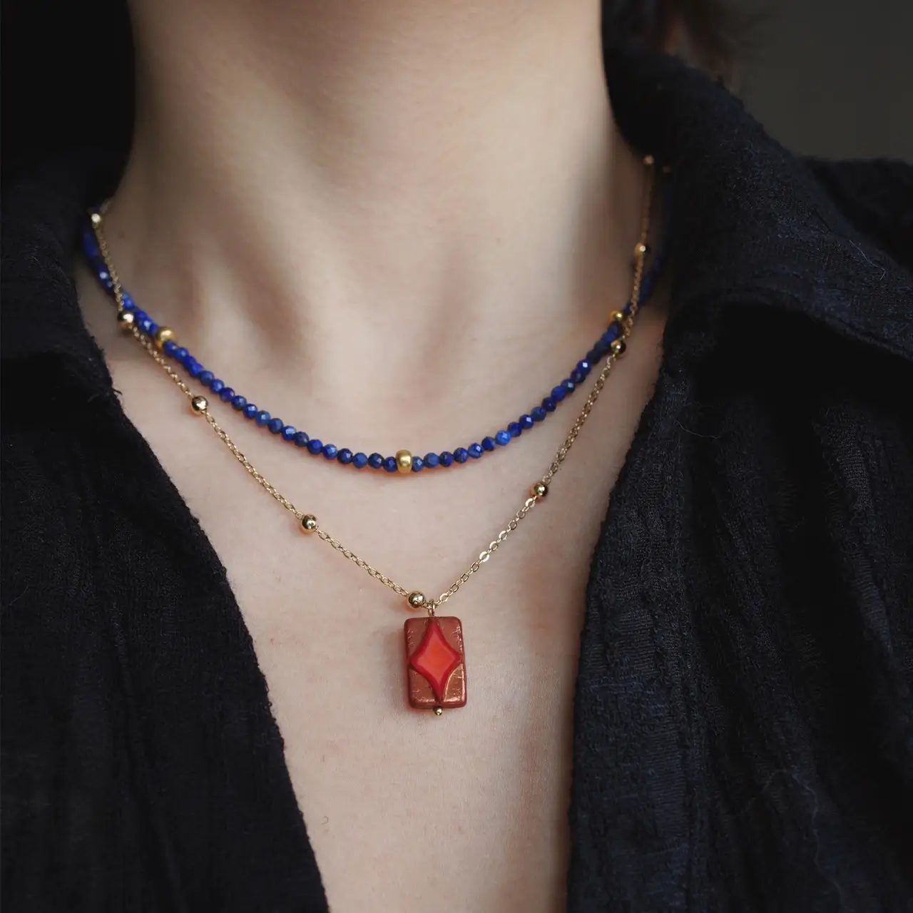 A model wearing a layered blue lapis beads and gold chain necklace with a black shirt.