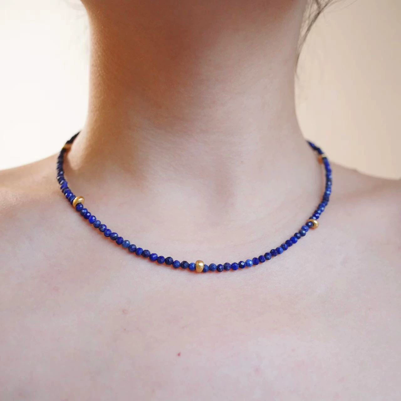 Blue lapis lazuli beaded choker necklace worn close to the clavicle.