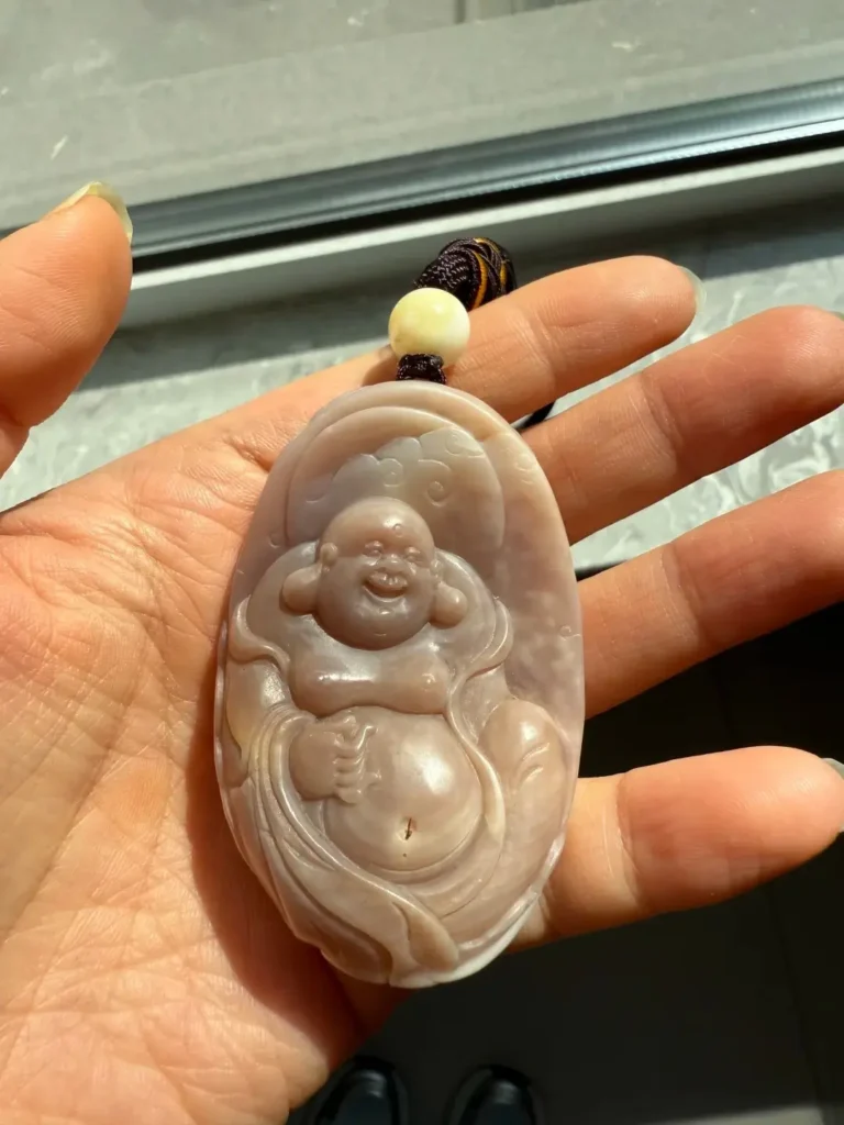 Carved purple Tridacna shell pendant featuring a Laughing Buddha design in lavender tones.