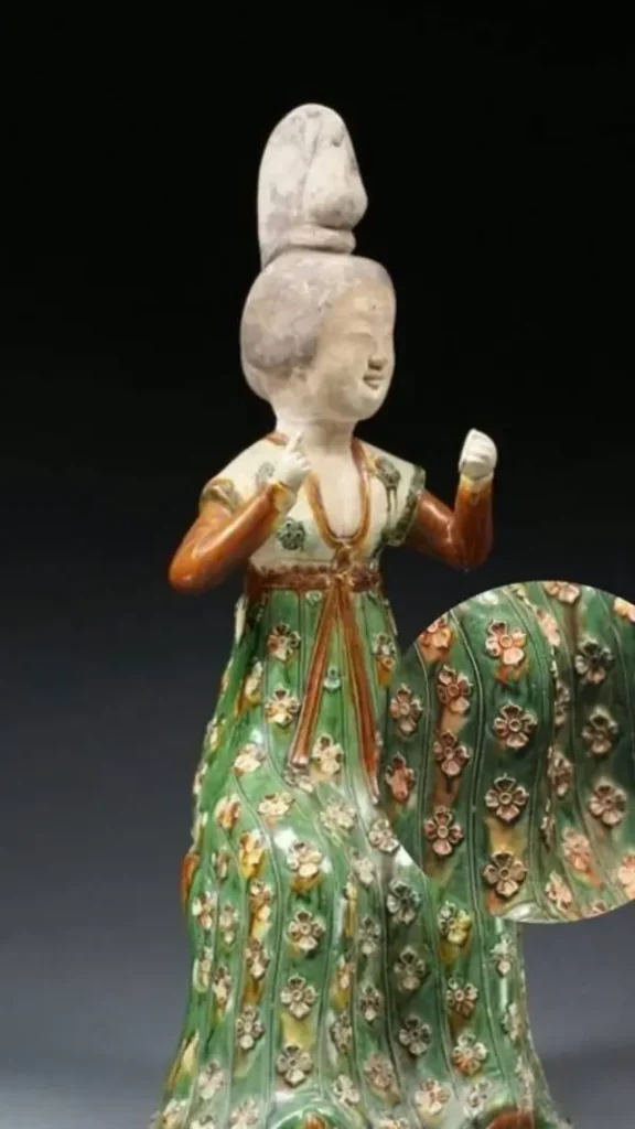 Tang sancai pottery figurine of a woman wearing a pleated skirt with repeating Persimmon Calyx motifs.