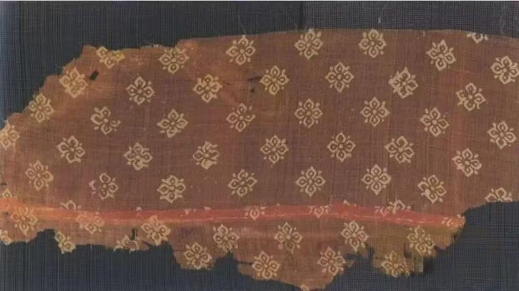 Tang wax-resist dyed silk fragment with repeated four-petal Persimmon Calyx Pattern motifs.