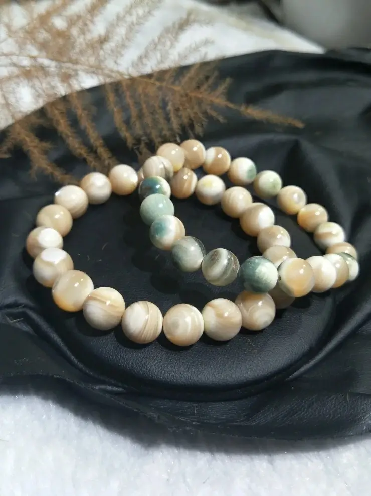 Two polished Turban Shell bead bracelets showing pearly nacre luster and natural greenish tones.