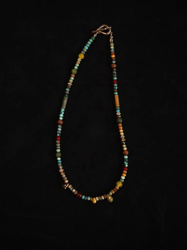 Handmade turquoise beaded necklace with natural stones and gold clasp on black background