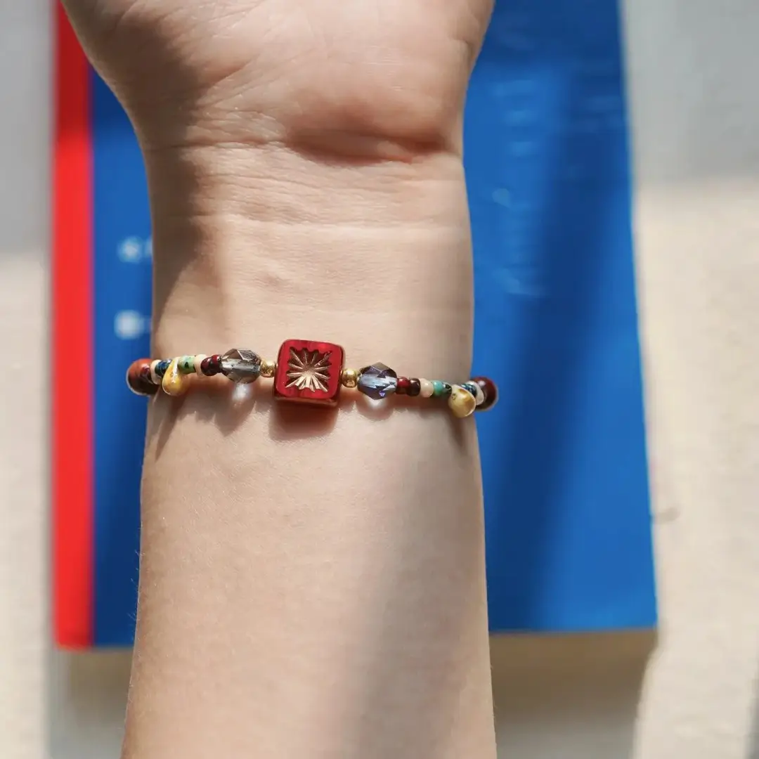 Vintage Czech glass beaded bracelet worn on a wrist with a blue book in the background.