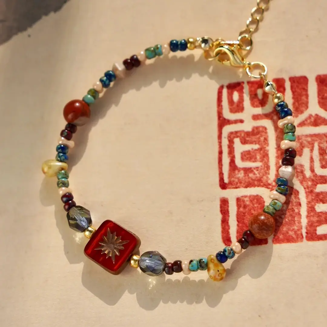 Vintage Czech glass beaded bracelet on vintage paper with a red seal in warm sunlight.