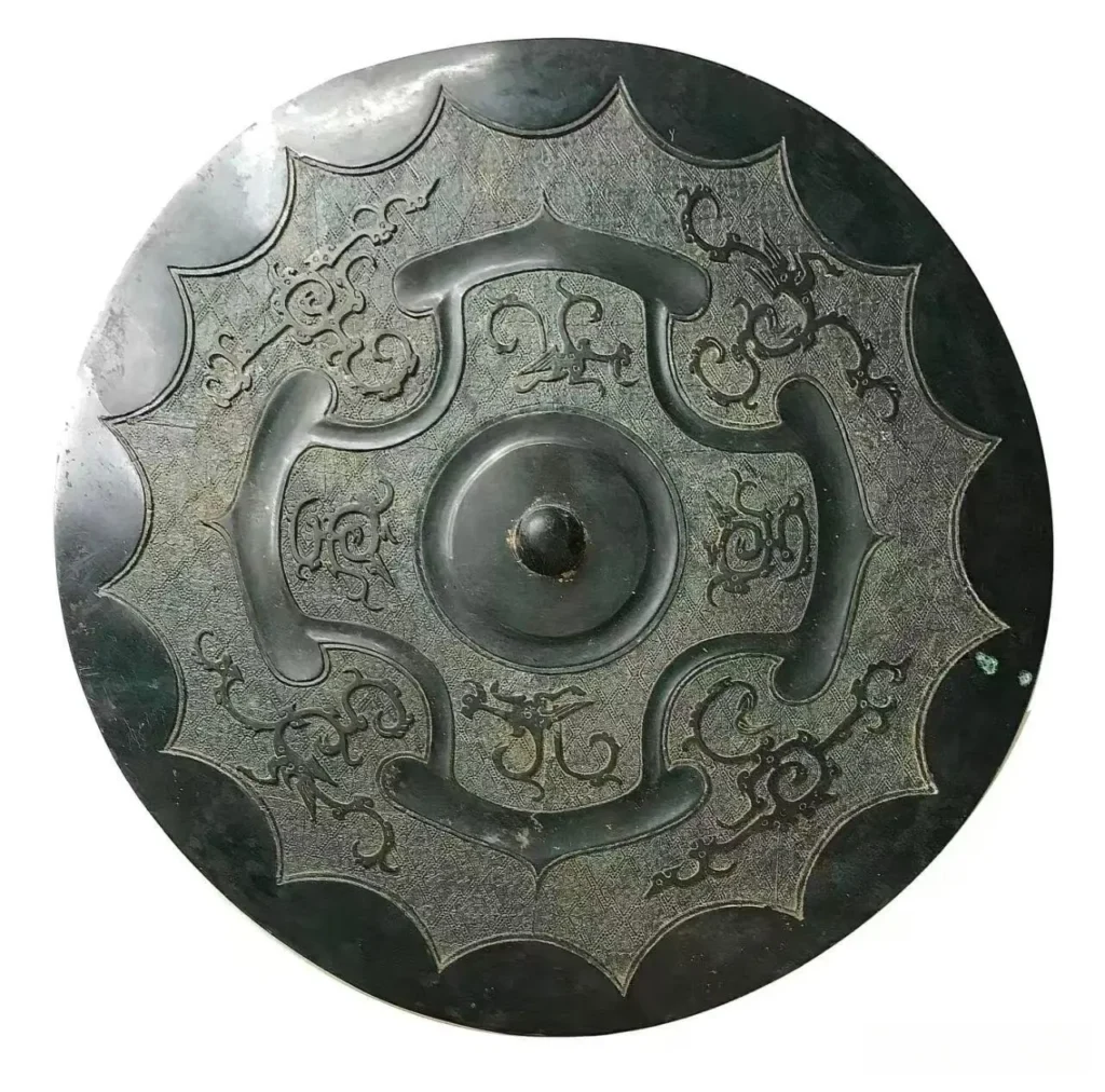 An ancient circular bronze mirror with intricate dragon, phoenix, and four-petal floral carvings.