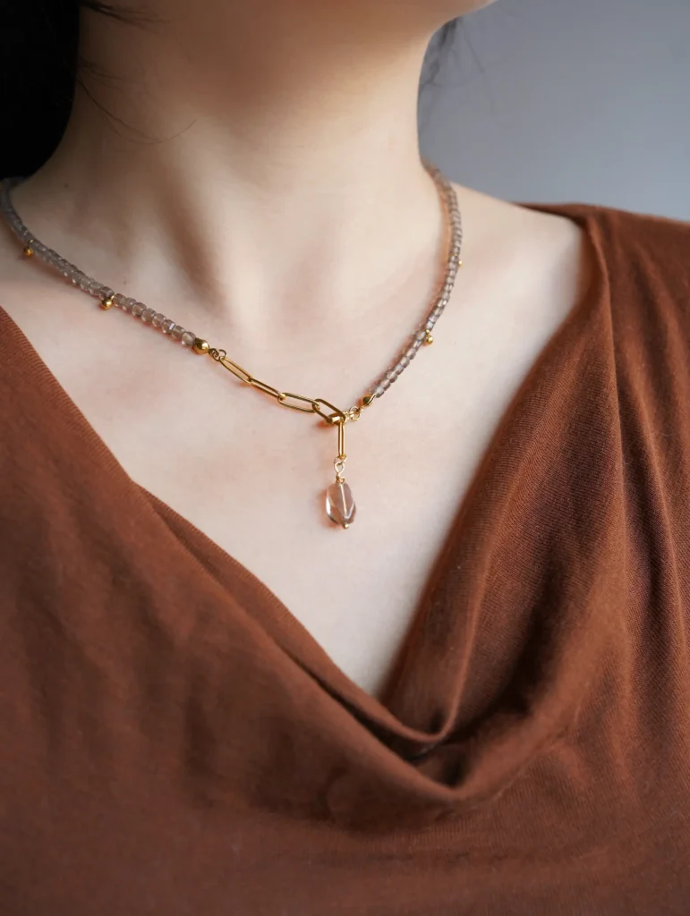 A woman wearing a Y-shape handmade necklace with natural ice obsidian and smoky quartz.